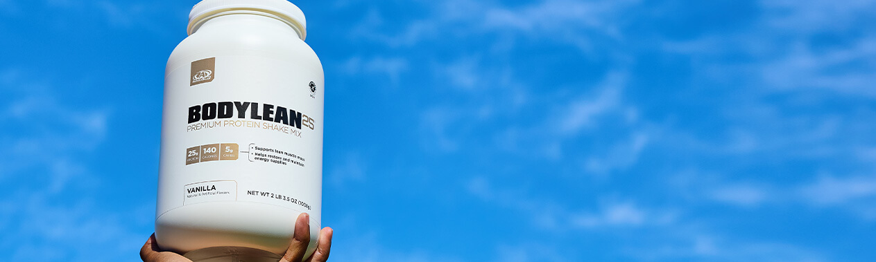 A hand holding up a large bottle of BodyLean25 in a bright blue sky.